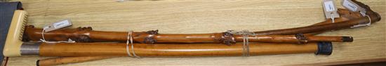 A fruitwood walking cane carved with multiple fox and dog masks and three other walking canes,